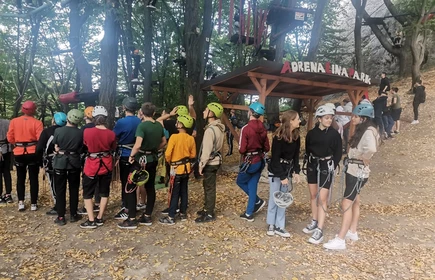 grupa uczniów stojąca w rzędzie przygotowująca się do wejścia na park linowy